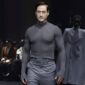 Miliarder teknologi Bryan Johnson mengenakan setelan abu-abu di catwalk Paris Fashion Week.